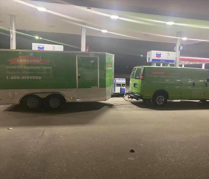 Green Van with Trailer Attached at Gas Station