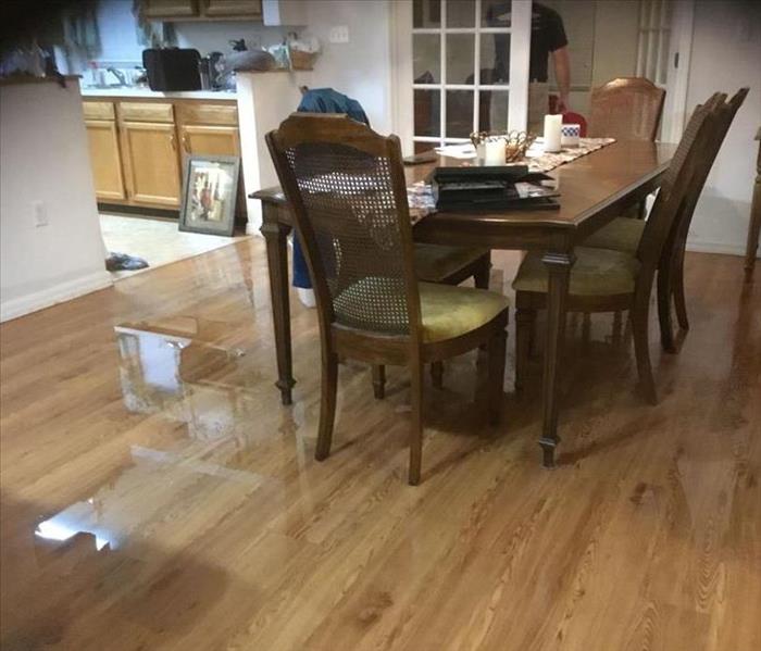 A table and chairs setting in water on a vinyl that looks like wood floor