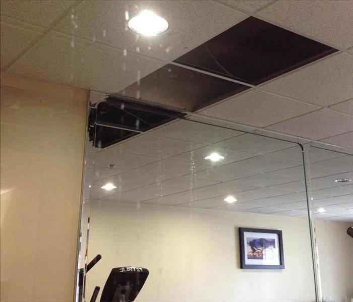 Water dripping from a knock down ceiling in a room filled with fitness equipment aka a gym