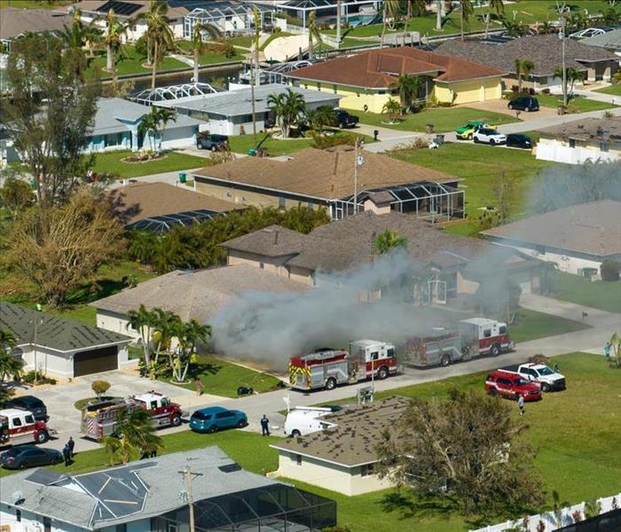 Burning residential house on fire with smoke and flames after short circuit spark ignited wooden roof damaged by hurricane